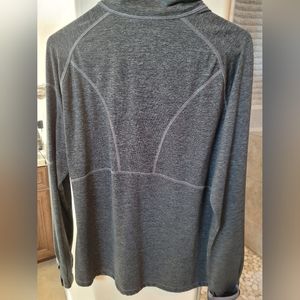 A grey Kirkland long-sleeve shirt With neck zipper and arm pocket with zipperTh